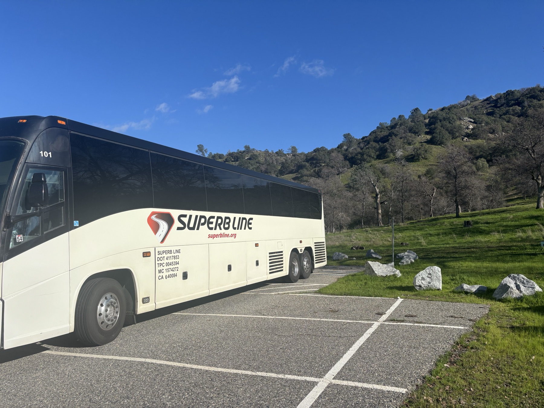 Superb Line full-size charter bus parked beside Central Valley hills